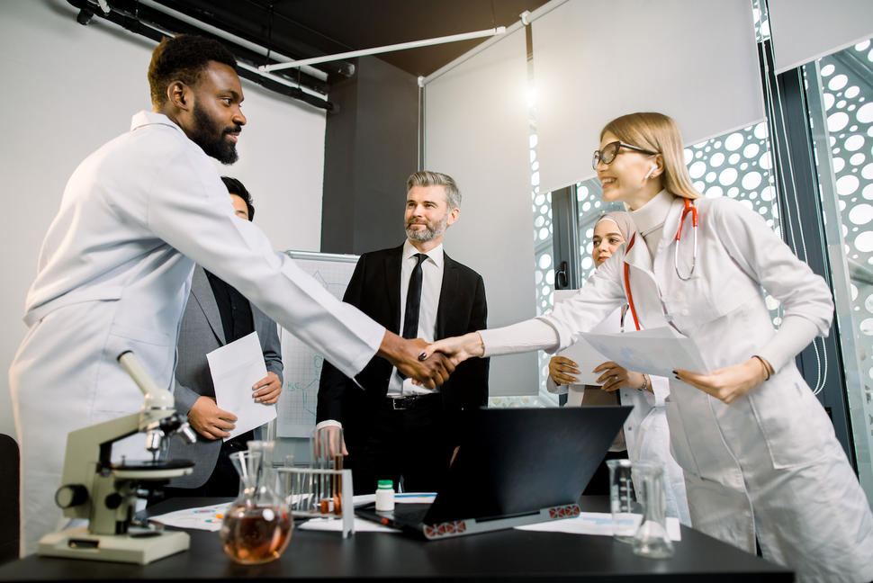 Handshake between researcher lab and business technology transfer negotiation deal