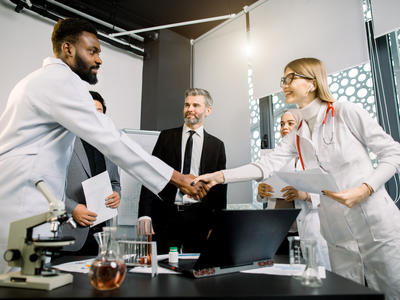 Handshake between researcher lab and business technology transfer negotiation deal