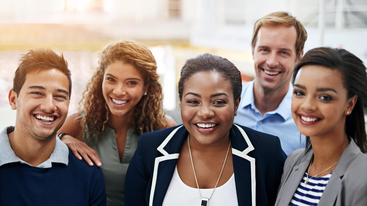 Young professional standing in a group smiling